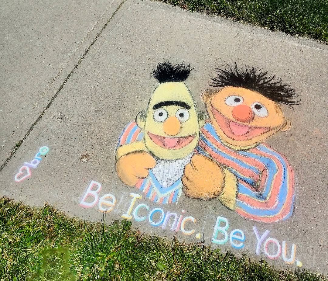 A colourful sidewalk chalk mural of Bert and Ernie with the words 'Be Iconic. Be You.', by Bronagh Joyce Morgan.